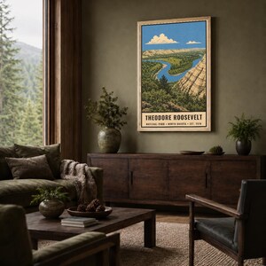 May include: A vertical rectangular wall art print featuring a landscape illustration of Theodore Roosevelt National Park in North Dakota. The artwork depicts a winding blue river, green trees, and tan rock formations under a blue sky with clouds.