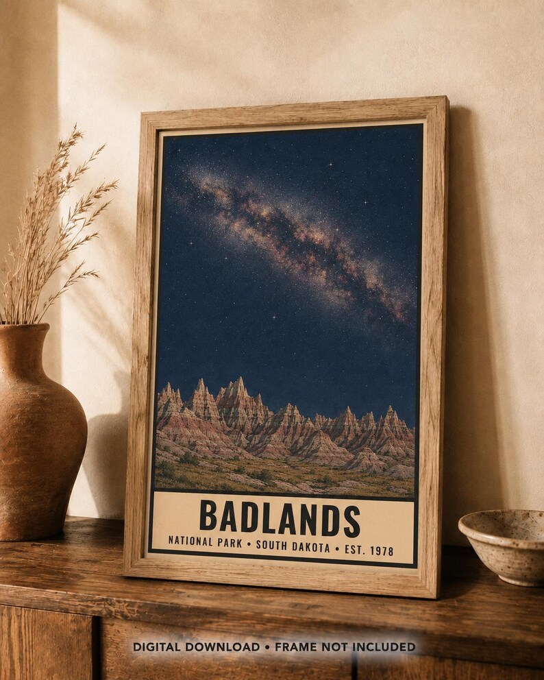 K&ouml;nnte beinhalten: Ein gerahmter vertikaler Wandkunstdruck des Badlands Nationalparks in South Dakota. Das Bild zeigt einen Sternenhimmel mit der Milchstra&szlig;e &uuml;ber zerkl&uuml;fteten, geschichteten Felsformationen. Der Text lautet BADLANDS NATIONAL PARK SOUTH DAKOTA EST. 1978.