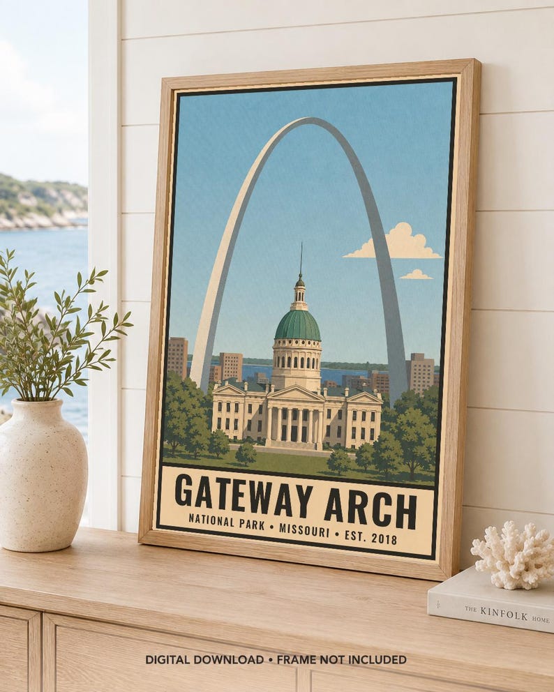 May include: A framed vertical art print featuring a stylized illustration of the Gateway Arch and the Old Courthouse in St. Louis, Missouri. The text at the bottom reads GATEWAY ARCH NATIONAL PARK MISSOURI EST. 2018 in bold black lettering.