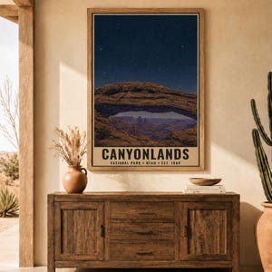 May include: A vertical wall art print featuring a night sky over Mesa Arch in Canyonlands National Park, Utah. The text reads CANYONLANDS NATIONAL PARK UTAH EST. 1964. The image displays a natural stone arch framing a canyon landscape under stars.