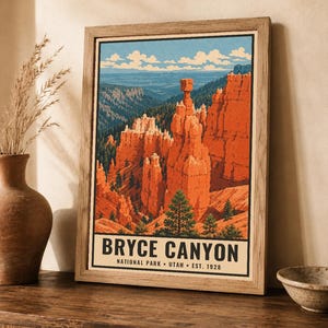 Op de afbeelding: Een ingelijste poster met een gestileerde illustratie van Bryce Canyon National Park in Utah. Het kunstwerk toont oranje rotsformaties, groene dennenbomen en een blauwe lucht met wolken. De tekst luidt BRYCE CANYON NATIONAL PARK UTAH EST. 1928.