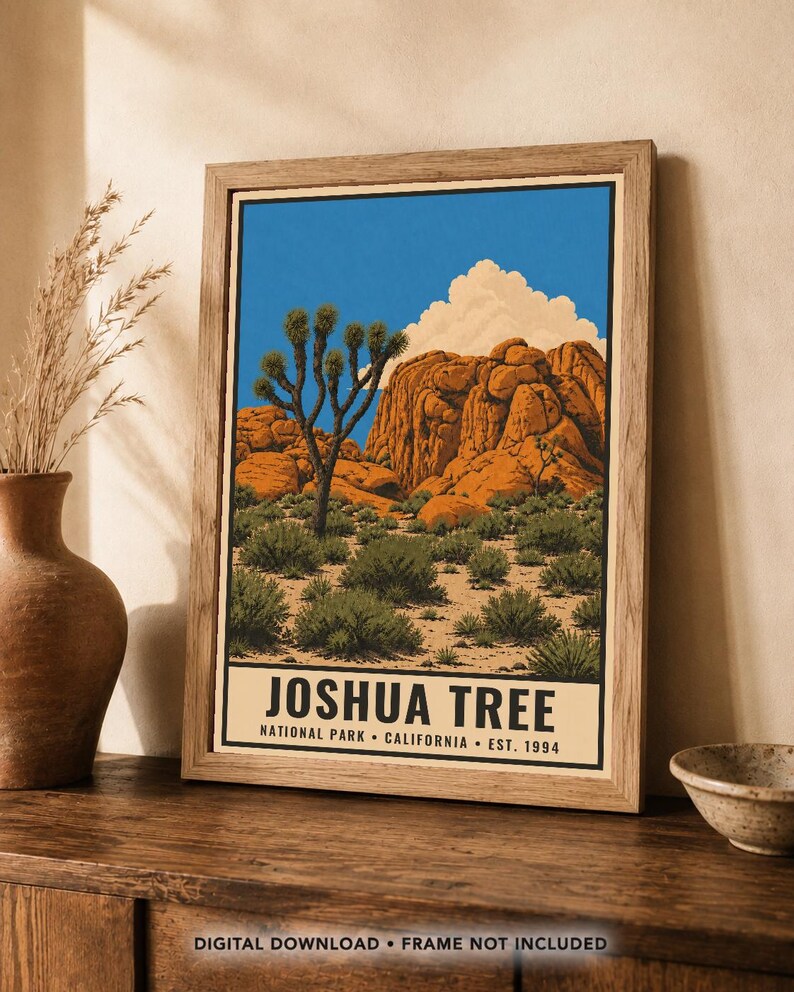 May include: A framed art print featuring a desert landscape with a Joshua tree, large orange rock formations, and a bright blue sky with white clouds. The text at the bottom reads JOSHUA TREE NATIONAL PARK CALIFORNIA EST. 1994 in black font.