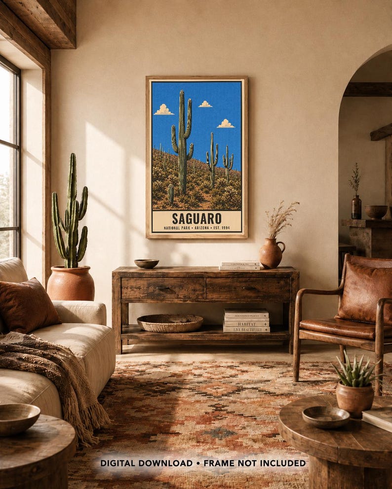 Op de afbeelding: Een verticale wandkunstprint met een woestijnlandschap met hoge groene saguaro-cactussen onder een helderblauwe lucht met kleine wolken. Het onderste gedeelte heeft een cr&egrave;mekleurige rand met de tekst SAGUARO NATIONAL PARK ARIZONA EST. 1994.