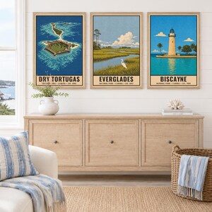 May include: Three framed vertical art prints featuring Florida national parks. The left print shows Dry Tortugas, the centre print depicts the Everglades with a white bird, and the right print displays the Biscayne lighthouse. Text includes park names.