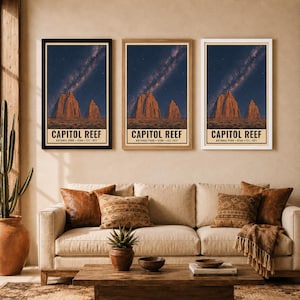 May include: Three identical vertical posters of Capitol Reef National Park, Utah, established 1971. Each print features a night sky with a visible Milky Way galaxy above red rock formations. The posters are displayed in black, wood, and white frames.