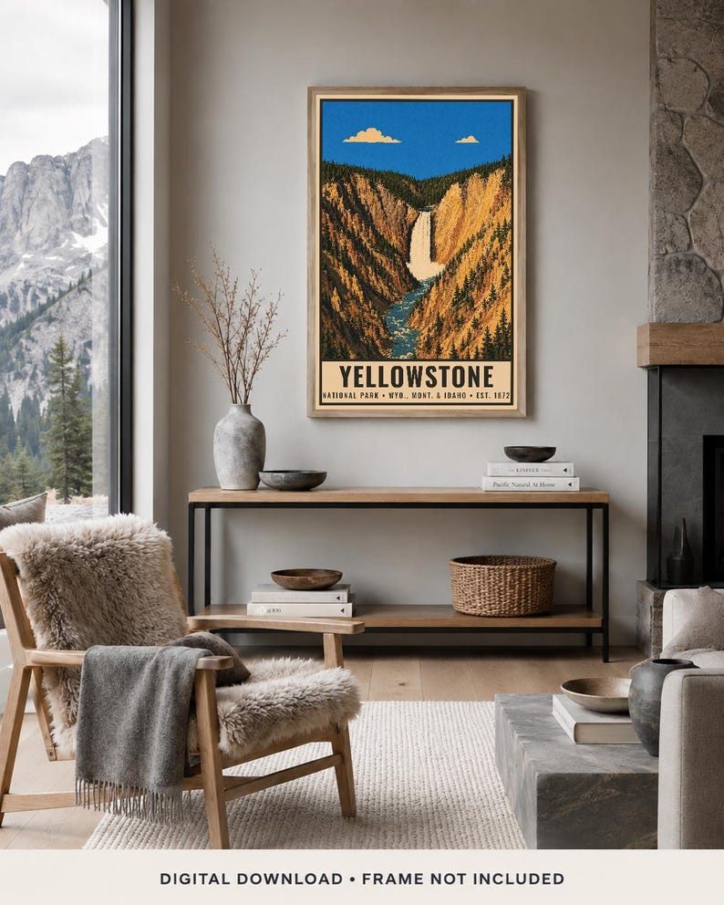 Op de afbeelding: Een ingelijste verticale wandkunstprint met een gestileerde illustratie van Yellowstone National Park met een waterval door een kloof, blauwe lucht met wolken en de tekst Yellowstone National Park, Wyo., Mont. & Idaho Est. 1872.
