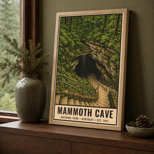 May include: A framed vertical poster depicting the entrance to Mammoth Cave National Park in Kentucky. The illustration features a stone staircase leading into a dark cave opening surrounded by lush green trees, with the text Mammoth Cave National Park Kentucky Est. 1941 printed at the bottom.