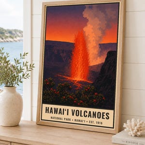 Puede incluir: Un p&oacute;ster enmarcado que representa una erupci&oacute;n volc&aacute;nica nocturna con lava de color naranja brillante y una columna de humo. El texto en la parte inferior dice HAWAI'I VOLCANOES NATIONAL PARK &bull; HAWAI'I &bull; EST. 1916. La obra muestra siluetas oscuras.