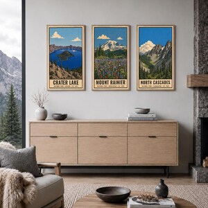 Może przedstawiać: Trzy pionowe, prostokątne plakaty ścienne w drewnianych ramach z ilustracjami park&oacute;w narodowych Crater Lake, Mount Rainier i North Cascades. Każdy wydruk zawiera nazwę parku, lokalizację oraz rok założenia czarną czcionką.