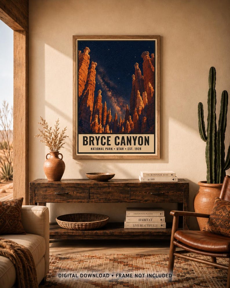 May include: A vertical wall art print featuring a night sky over Bryce Canyon, Utah, with orange rock formations and a starry Milky Way. The text reads BRYCE CANYON NATIONAL PARK UTAH EST. 1928. The print is displayed in a wooden frame on a wall.
