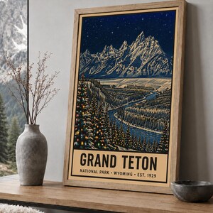 May include: A framed vertical poster featuring a nighttime illustration of the Grand Teton mountain range under a starry sky. The scene includes a winding river, snow-covered pine trees with colorful lights, and text reading GRAND TETON NATIONAL PARK WYOMING EST. 1929.