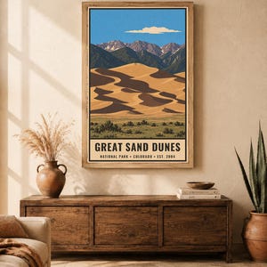 K&ouml;nnte beinhalten: Ein vertikaler Wandkunstdruck mit einer stilisierten Illustration des Great Sand Dunes Nationalparks in Colorado. Das Bild zeigt goldene Sandd&uuml;nen, gr&uuml;ne Vegetation, dunkle Berge und einen blauen Himmel mit einer einzelnen Wolke. Der Text lautet: GREAT SAND DUNES NATIONAL PARK &bull; COLORADO &bull; EST. 2004.