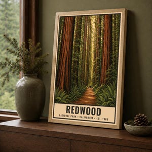 May include: A rectangular poster in a light wood frame featuring a vertical forest scene with tall redwood trees, green ferns, and a dirt path. The text at the bottom reads REDWOOD NATIONAL PARK CALIFORNIA EST. 1968 in black capital letters.