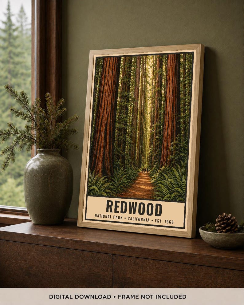 May include: A rectangular poster in a light wood frame featuring a vertical forest scene with tall redwood trees, green ferns, and a dirt path. The text at the bottom reads REDWOOD NATIONAL PARK CALIFORNIA EST. 1968 in black capital letters.