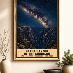 May include: A rectangular wall poster in a light wood frame featuring a night sky with a visible Milky Way galaxy above the deep, dark rock formations of the Black Canyon of the Gunnison. The text reads: BLACK CANYON OF THE GUNNISON NATIONAL PARK COLORADO EST. 1999.