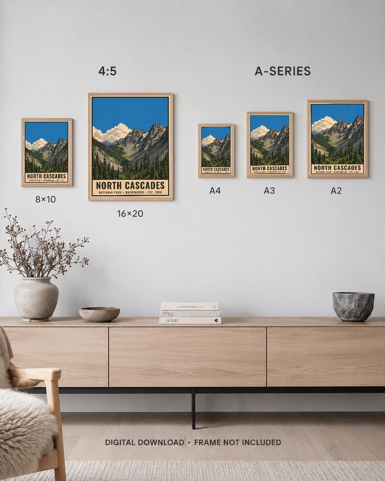 Op de afbeelding: Een collectie van vijf ingelijste kunstprints met het North Cascades National Park met berg- en boslandschappen. De prints zijn gelabeld met de maten 8x10, 16x20, A4, A3 en A2. De tekst luidt North Cascades National Park Washington Est 1968.