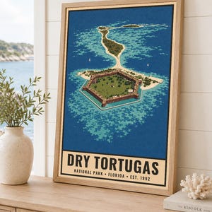 May include: A framed vertical poster featuring an aerial illustration of the hexagonal Fort Jefferson surrounded by turquoise water and sandy islands. The text at the bottom reads DRY TORTUGAS NATIONAL PARK FLORIDA EST. 1992 in black lettering.