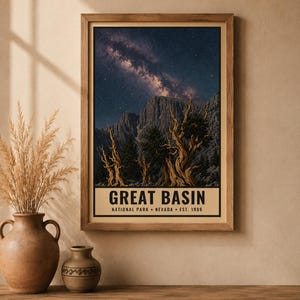 May include: A framed vertical poster featuring a night sky with the Milky Way galaxy above rugged mountain peaks and twisted bristlecone pine trees. The text at the bottom reads GREAT BASIN NATIONAL PARK NEVADA EST. 1986 in bold black lettering.