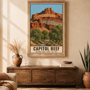 Op de afbeelding: Een verticale wandkunstprint met een landschapsillustratie van Capitol Reef National Park in Utah. De afbeelding toont rode rotskliffen, groene bomen en een beek onder een blauwe lucht, met de tekst CAPITOL REEF NATIONAL PARK UTAH EST. 1971.