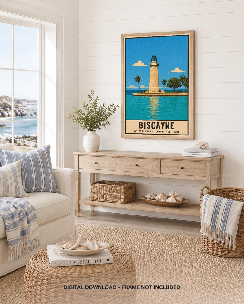 May include: A framed vertical wall art print featuring a stylized illustration of a lighthouse on a small island surrounded by turquoise water under a bright blue sky, with the text BISCAYNE NATIONAL PARK FLORIDA EST. 1980 printed at the bottom.