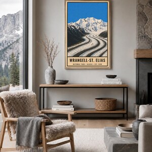 K&ouml;nnte beinhalten: Ein vertikaler Wandkunstdruck mit einer Landschaftsillustration des Wrangell-St. Elias Nationalparks in Alaska. Das Bild zeigt einen schneebedeckten Berggipfel &uuml;ber einem Gletscher mit dunklen Mor&auml;nenlinien sowie den Text WRANGELL-ST. ELIAS.