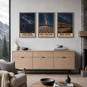 May include: Three vertical framed wall art prints featuring night sky landscapes of Black Canyon of the Gunnison, Great Sand Dunes, and Mesa Verde National Parks. Each print displays a starry galaxy above the park terrain with text below.