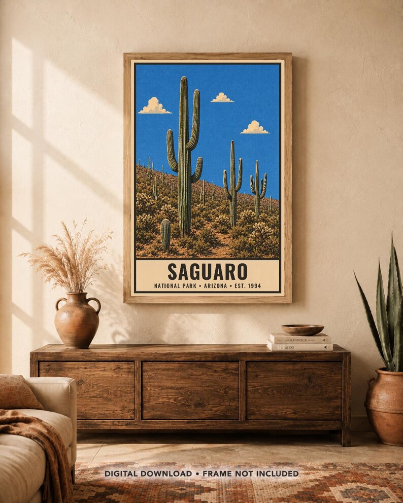 Op de afbeelding: Een verticale wandkunstprint met een woestijnlandschap met hoge groene saguaro-cactussen onder een helderblauwe lucht met witte wolken. Het onderste gedeelte bevat de tekst SAGUARO NATIONAL PARK ARIZONA EST. 1994 in een vetgedrukt zwart lettertype.