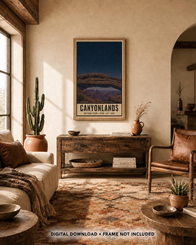May include: A vertical wall art print featuring a night sky over the rock arch formation in Canyonlands National Park, Utah. The text reads CANYONLANDS NATIONAL PARK UTAH EST. 1964. The print is displayed in a wooden frame on a beige wall.