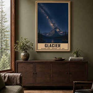 May include: A vertical wall art print featuring a night landscape of Glacier National Park in Montana. The image displays a snow-capped mountain peak under a starry sky with the Milky Way, above a dark lake. Text reads: GLACIER NATIONAL PARK MONTANA EST. 1910.