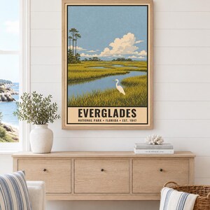 Pu&ograve; includere: Un poster verticale incorniciato che raffigura l'Everglades National Park in Florida. L'illustrazione mostra un'egretta bianca in una palude erbosa sotto un cielo azzurro con nuvole. Il testo recita EVERGLADES NATIONAL PARK FLORIDA EST. 1947.
