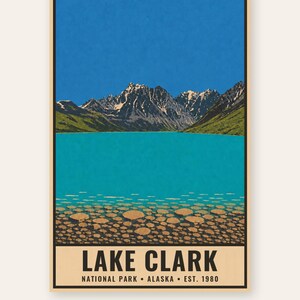 Pode incluir: Um cartaz retangular com uma ilustra&ccedil;&atilde;o da paisagem do Lago Clark no Alasca. A cena mostra um c&eacute;u azul brilhante, montanhas escarpadas cobertas de neve, colinas verdes e um lago turquesa com pedras redondas vis&iacute;veis no fundo. O texto diz LAKE CLARK NATIONAL PARK ALASKA EST. 1980.