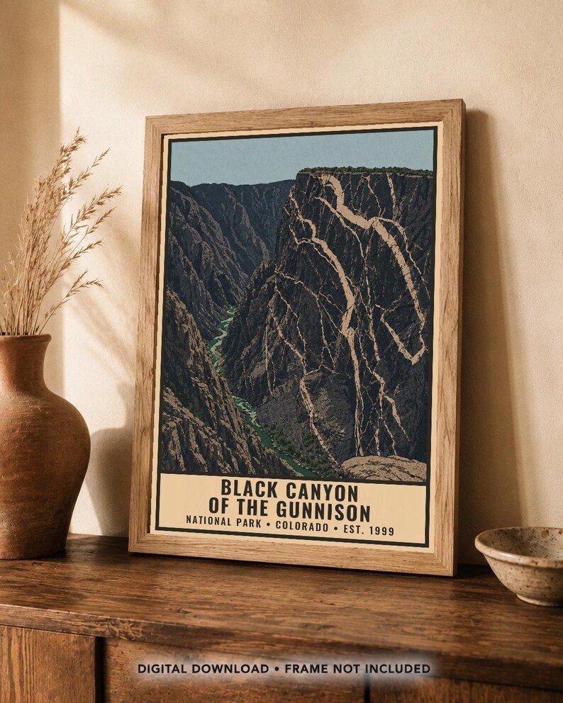 Op de afbeelding: Een ingelijste poster met een grafische illustratie van de Black Canyon of the Gunnison met een kronkelende rivier aan de basis en steile kliffen. De tekst luidt: BLACK CANYON OF THE GUNNISON NATIONAL PARK COLORADO EST. 1999. De lijst is van licht hout.