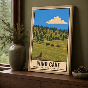 K&ouml;nnte beinhalten: Ein gerahmtes Poster mit einer Landschaftsillustration des Wind Cave Nationalparks in South Dakota. Das Bild zeigt einen grasbewachsenen H&uuml;gel mit Kiefern, drei Bisons und einem Pr&auml;riehund unter einem blauen Himmel mit einer Wolke. Der Text lautet: WIND CAVE NATIONAL PARK SOUTH DAKOTA EST. 1903.