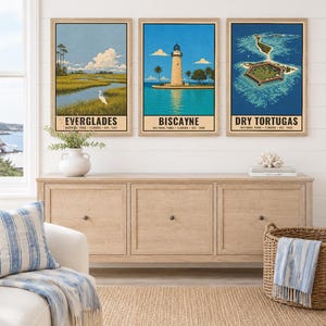 K&ouml;nnte beinhalten: Drei gerahmte vertikale Wandbilder mit Illustrationen von Nationalparks in Florida. Das linke Bild zeigt die Everglades mit einem wei&szlig;en Vogel, das mittlere den Biscayne-Leuchtturm und das rechte das Fort von Dry Tortugas.
