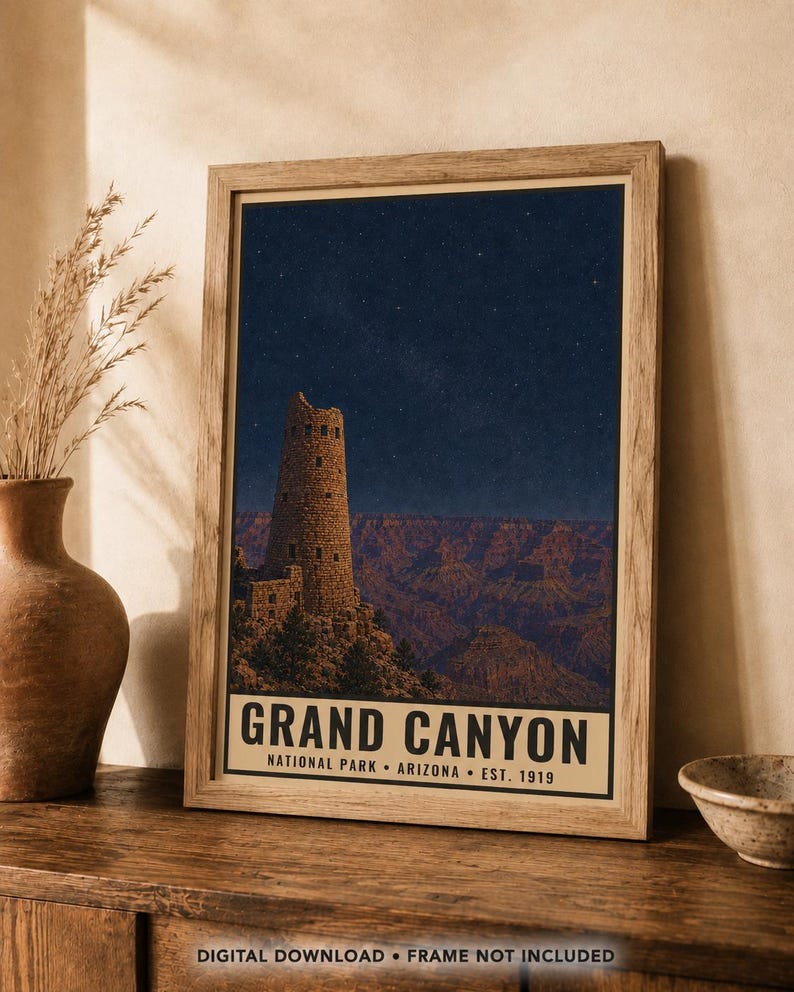 May include: A framed vertical poster featuring a night scene of the Grand Canyon with the Desert View Watchtower under a starry sky. The text at the bottom reads GRAND CANYON NATIONAL PARK ARIZONA EST. 1919. The print is in a light wood frame.