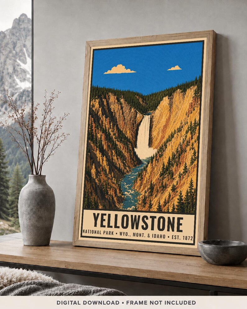 Op de afbeelding: Een ingelijste verticale poster met een gestileerde illustratie van een waterval die door een diepe kloof met dennenbomen stroomt, onder een helderblauwe lucht met twee wolken. De tekst luidt YELLOWSTONE NATIONAL PARK WYO., MONT. & IDAHO EST. 1872.