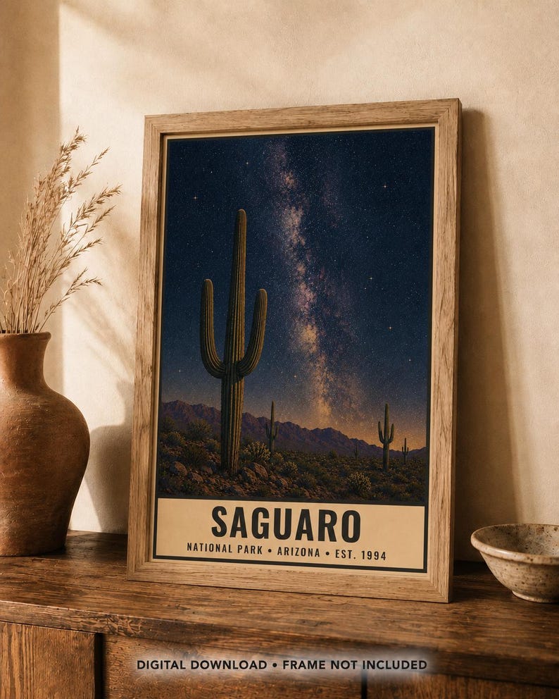 Puede incluir: Una l&aacute;mina de arte mural vertical enmarcada que muestra un cielo nocturno con la V&iacute;a L&aacute;ctea sobre un paisaje des&eacute;rtico con cactus saguaro y monta&ntilde;as. La parte inferior contiene el texto SAGUARO NATIONAL PARK ARIZONA EST. 1994 en letras negras.