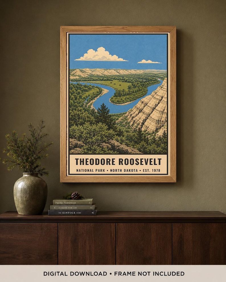 May include: A rectangular wall art print in a wooden frame depicting a landscape of Theodore Roosevelt National Park in North Dakota. The illustration features a winding blue river, green forests, and layered rock formations under a blue sky.