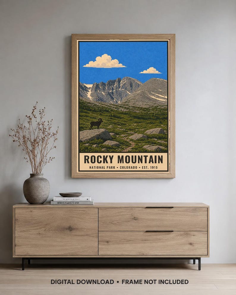 May include: A vertical rectangular wall art print featuring a landscape of Rocky Mountain National Park. The illustration shows a bighorn sheep on a rock, green meadows, and snow-capped mountains under a blue sky. Text reads ROCKY MOUNTAIN NATIONAL PARK COLORADO EST. 1915.