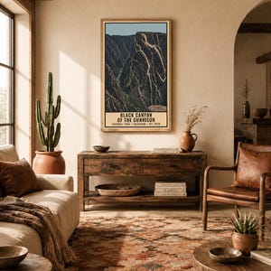 Op de afbeelding: Een verticale rechthoekige wandkunstprint met een gestileerde illustratie van het Black Canyon of the Gunnison National Park in Colorado. Het kunstwerk toont diepe kloofwanden, een rivier en de tekst Black Canyon of the Gunnison.