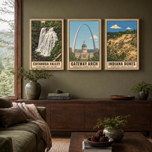 Może przedstawiać: Trzy pionowe wydruki artystyczne w jasnych drewnianych ramach z ilustracjami park&oacute;w narodowych Cuyahoga Valley, Gateway Arch i Indiana Dunes. Każdy wydruk zawiera nazwę parku, lokalizację i rok założenia czarnym tekstem na dole.