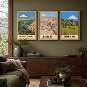 May include: Three vertical rectangular wall art prints featuring illustrations of Theodore Roosevelt, Badlands, and Wind Cave National Parks. Each print displays a landscape scene under a blue sky with white clouds and includes text at the bottom.