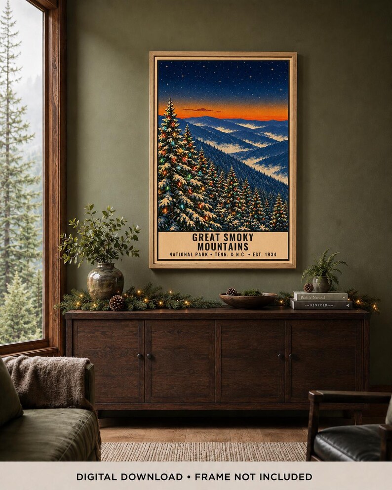 May include: A vertical rectangular poster in a light wood frame depicting the Great Smoky Mountains National Park at twilight. The artwork features snow-covered pine trees with colorful lights, a starry sky, and the text Great Smoky Mountains National Park Tenn. & N.C. Est. 1934.