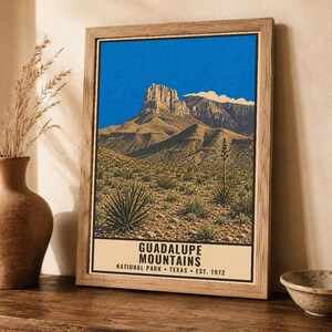 K&ouml;nnte beinhalten: Ein gerahmter Kunstdruck mit einer Landschaft des Guadalupe Mountains National Park in Texas. Das Bild zeigt einen felsigen Berggipfel unter einem leuchtend blauen Himmel, mit W&uuml;stenvegetation im Vordergrund und Text am unteren Rand.