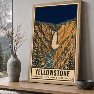May include: A framed poster print of Yellowstone National Park featuring a waterfall, rocky canyon walls, and two evergreen trees decorated with colorful Christmas lights under a starry night sky, with the text Yellowstone National Park Wyo. Mont. & Idaho Est. 1872.