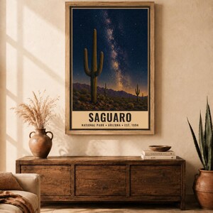 Puede incluir: Un p&oacute;ster rectangular vertical que muestra un cactus Saguaro en un paisaje des&eacute;rtico bajo un cielo estrellado con la V&iacute;a L&aacute;ctea. El texto dice SAGUARO NATIONAL PARK ARIZONA EST. 1994 en letras may&uacute;sculas negras sobre un fondo de color crema.
