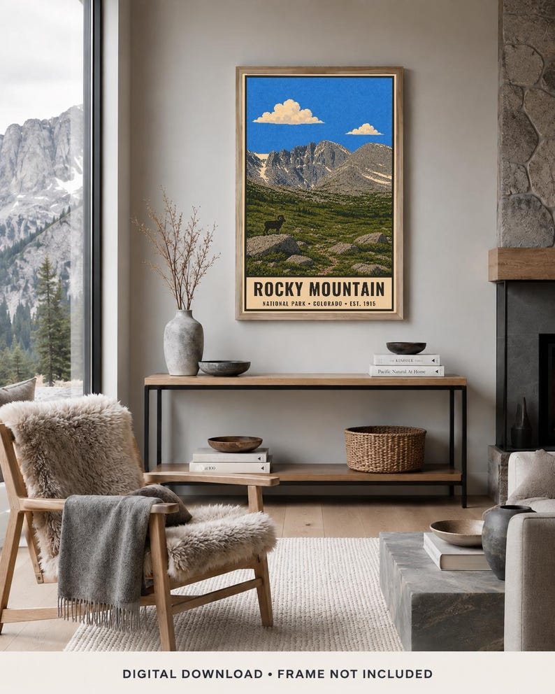 May include: A vertical wall art print featuring a landscape illustration of Rocky Mountain National Park in Colorado. The artwork depicts jagged mountain peaks under a blue sky with clouds, a green meadow, and a bighorn sheep. Text reads ROCKY MOUNTAIN NATIONAL PARK COLORADO EST. 1915.