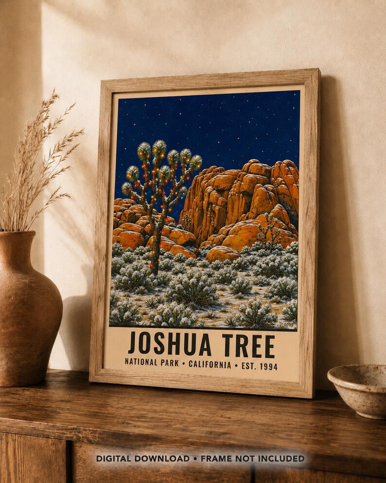 May include: A framed art print featuring a night scene of Joshua Tree National Park with a starry sky, orange rock formations, and a Joshua tree decorated with lights. The text reads JOSHUA TREE NATIONAL PARK CALIFORNIA EST. 1994.