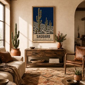 May include: A rectangular wall art print featuring a dark blue night sky with stars over a desert landscape of saguaro cacti. The bottom section contains the text SAGUARO NATIONAL PARK ARIZONA EST. 1994 in black capital letters on a cream background.