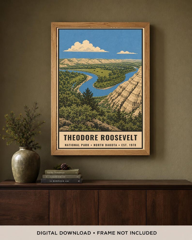 May include: A rectangular wall art print in a wooden frame depicting a landscape of Theodore Roosevelt National Park in North Dakota. The illustration features a winding blue river, green forests, and layered rock formations under a blue sky.